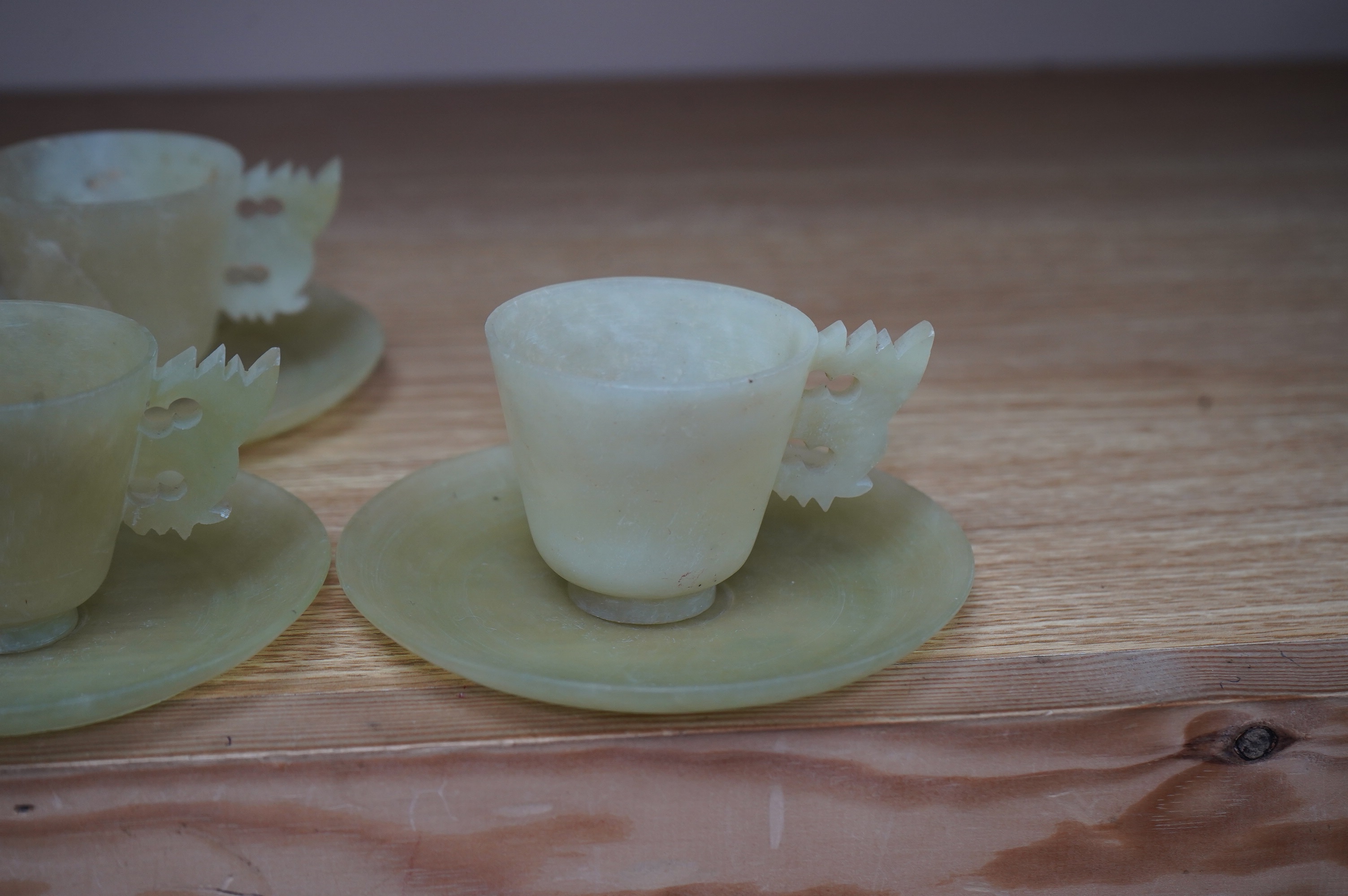 A set of seven Chinese bowenite jade cups and eight saucers, 11cm in diameter. Condition - fair to good